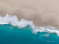 Overhead aerial view of Injidup Beach in Yallingup, with a foamy white wave sweeping diagonally between turquoise ocean and smooth pale sand.